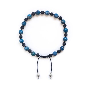 May include: A blue and black beaded bracelet with silver accents. The bracelet is made with blue gemstone beads and black lava rock beads.