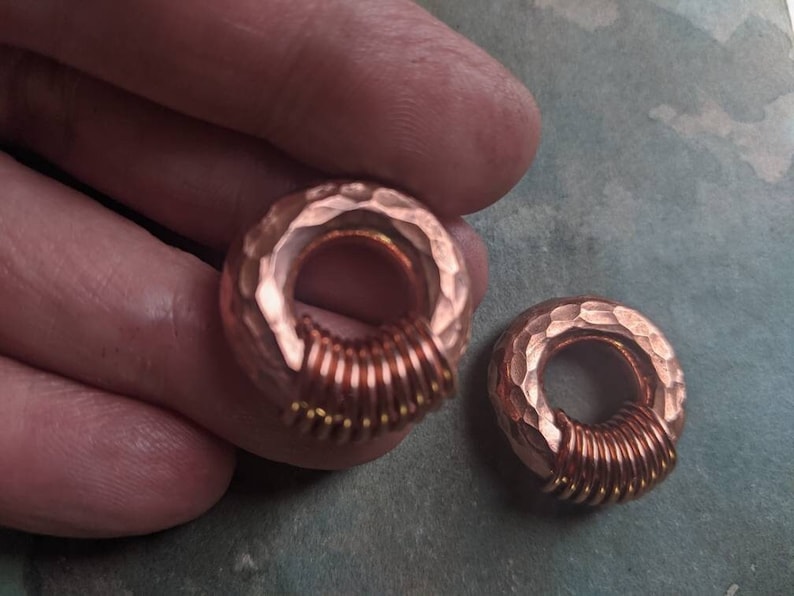 Puede incluir: Dos anillos de cobre con textura martillada y un dise&ntilde;o de alambre en espiral. Los anillos son de un color cobre c&aacute;lido y tienen un aspecto r&uacute;stico.