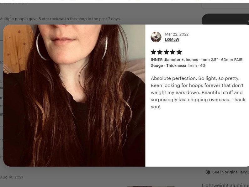 May include: Five star review for a pair of silver hoop earrings. The review states "Absolute perfection. So light, so pretty. Been looking for hoops forever that don't weight my ears down. Beautiful stuff and surprisingly fast shipping overseas. Thank you!" The review also includes the details: "INNER diameter &plusmn;, inches - mm: 2.5 - 63mm PAIR Gauge - Thickness: 4mm - 6G"