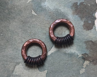 May include: Two copper rings with a hammered finish, each with a band of black metal rings around the center.