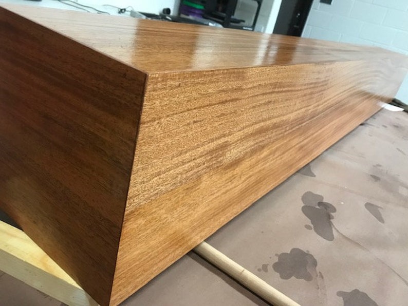 May include: A long, rectangular wooden shelf with a smooth, polished finish. The shelf is made of light brown wood with a natural grain pattern.