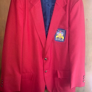 May include: A bright red blazer with a navy blue lining and gold buttons. The blazer has a VICA patch on the chest and the number "4z" written on the lining. The blazer is hanging on a clear hanger.