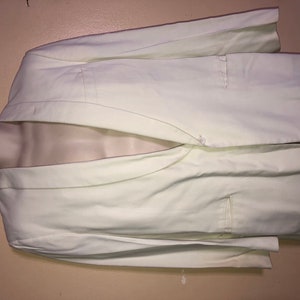 May include: A white blazer with a single button closure and a pocket on the left side.