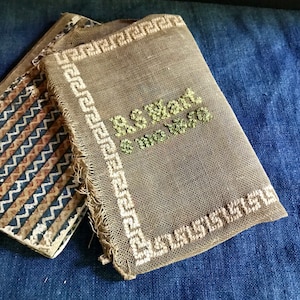 以下が含まれることがあります： 白いギリシャの鍵の縁取りと緑色の糸で「remarkable」と刺繍された、茶色のキャンバス製のニードルポイントです。