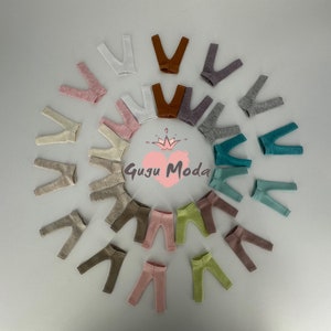 May include: A variety of colors of doll leggings arranged in a circle. The leggings are made of a soft, stretchy fabric. The text "Gugu Moda" is visible in the center of the circle.
