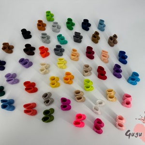 May include: A variety of felt boots in different colors, including red, blue, green, yellow, and purple. The boots are arranged in a pattern on a white background. The text "Gugu Moda" is visible in the lower right corner of the image.