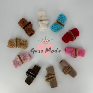 Könnte beinhalten: Sortiment von zehn Paaren flauschiger, bunter und brauner Stiefelmanschetten mit einem braunen Gummiband. Die Stiefelmanschetten sind in einem Kreis auf weißem Hintergrund angeordnet. Der Text "Gugu Moda" befindet sich in der Mitte des Kreises.
