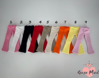 Könnte beinhalten: Neun Paar Puppen-Schlaghosen in verschiedenen Farben, darunter rosa, weiß, schwarz, rot, beige, grau, orange, gelb und hellrosa. Die Hosen sind von 1 bis 9 nummeriert.