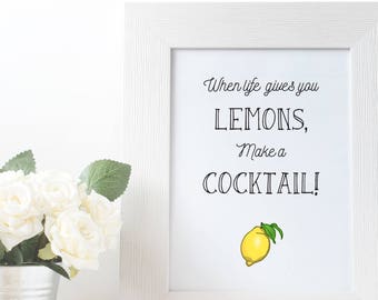May include: White framed print with the text "When life gives you lemons, make a cocktail!" and a yellow lemon illustration. A small metal bucket with white roses and green leaves sits to the left of the frame.