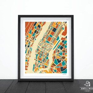 May include: A framed print of a colorful map of New York City. The map is divided into blocks of orange, yellow, blue, and brown. The map is set against a cream background.
