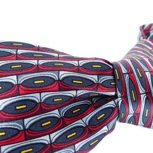 May include: A blue, red, and yellow patterned silk necktie with a geometric design.