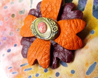 Upcycled antique rust and burgundy magnetic leather flower with gold coral center. Silk covered back button. Wear a bit of history!