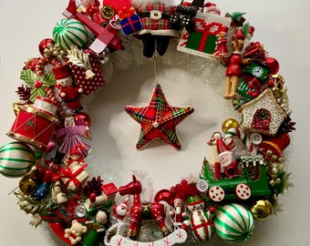 Puede incluir: Una corona navideña festiva adornada con adornos en miniatura. La corona presenta una variedad de decoraciones, incluyendo figuras de Papá Noel, soldados de juguete, bolas a rayas verdes y blancas y una estrella a cuadros. Una colorida decoración navideña.