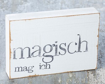 May include: White wooden sign with black lettering that reads "magisch" and "mag ich".