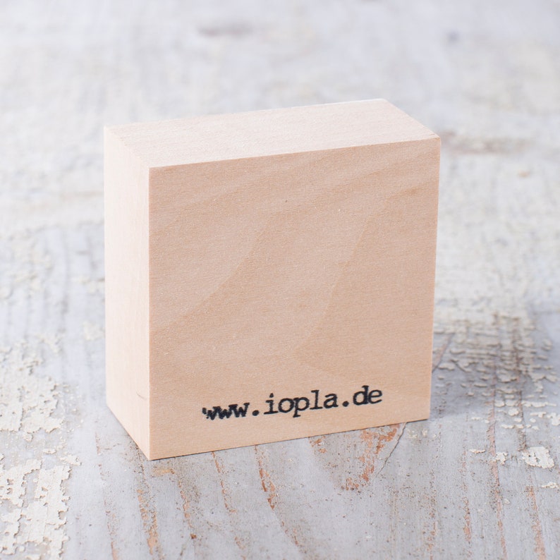 May include: A wooden block stamp with the text "www.iopla.de" printed on the bottom.