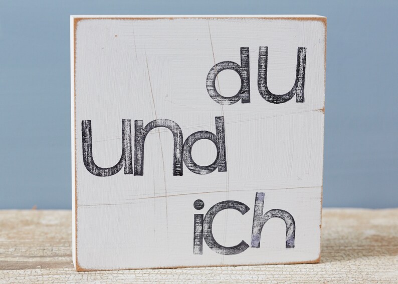 Puede incluir: Un letrero de madera blanco con letras negras que dice "du und ich".
