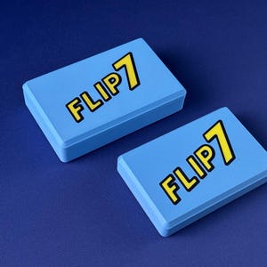 Puede incluir: Dos cajas rectangulares de color azul claro con el texto "FLIP 7" en amarillo con un contorno negro. Las cajas est&aacute;n sobre una superficie azul oscuro. Las cajas parecen ser cajas de juego.