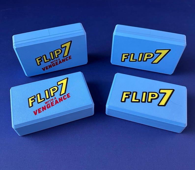 Puede incluir: Cuatro cajas de juego azul claro con el texto "FLIP 7" en amarillo y negro, y "WITH A VENGEANCE" en rojo. Las cajas rectangulares tienen una superficie ligeramente texturizada, sobre un fondo azul oscuro.