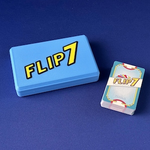 Puede incluir: Una caja de juego azul claro y una baraja de cartas sobre una superficie azul. La caja y las cartas presentan el texto "FLIP 7" en amarillo con un contorno negro. Las cartas tienen un borde decorativo.