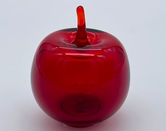 May include: A vibrant red glass apple sculpture with a stem. The apple is a solid, rounded shape with a glossy finish. The stem is a lighter shade of red, adding contrast to the design. This decorative piece is ideal for home decor.