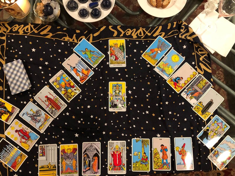 May include: A tarot card reading spread laid out on a black fabric with gold stars. The cards are arranged in a diamond shape with the Emperor card in the center. The cards are from the Rider-Waite tarot deck.