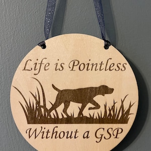 May include: A round wooden sign with the text "Life is Pointless Without a GSP" and a silhouette of a German Shorthaired Pointer dog in the grass.
