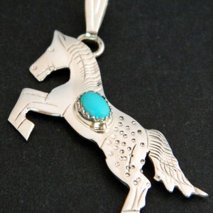 May include: Sterling silver pendant featuring a rearing horse design with a turquoise stone set in the center.