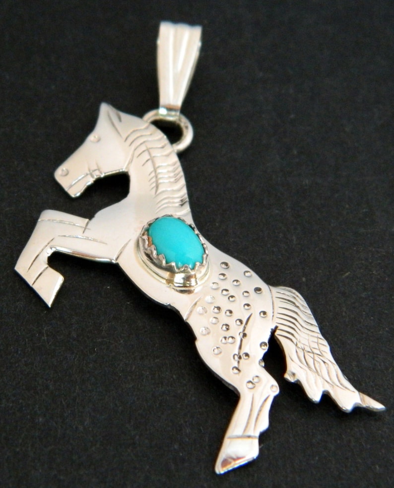 May include: Sterling silver pendant featuring a rearing horse design with a turquoise stone set in the center.