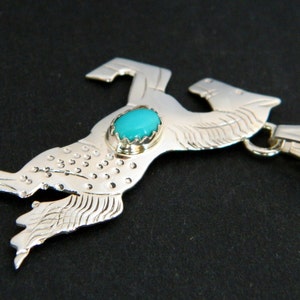 May include: A silver pendant featuring a stylized horse design with a turquoise stone set in the center. The pendant has a loop for attaching to a chain.