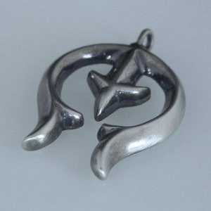 May include: A silver pendant in the shape of a crescent moon with a stylized arrow design in the center.