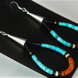 May include: A pair of dangle earrings with turquoise, coral, and black beads. The earrings are made of silver and have a cone-shaped top.