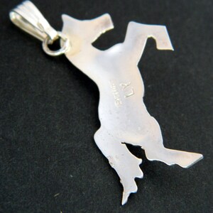 May include: Silver pendant in the shape of a rearing horse. The back of the pendant is stamped with "Sterling" and "LY".
