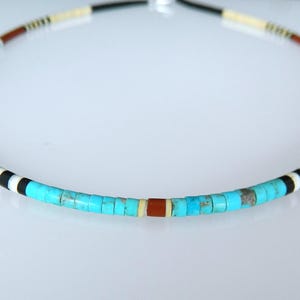 May include: A beaded necklace featuring a repeating pattern of small cylindrical turquoise, black, white, and reddish-brown beads. The strand is arranged in a circular shape, showcasing a vibrant color palette with turquoise as the central focus.