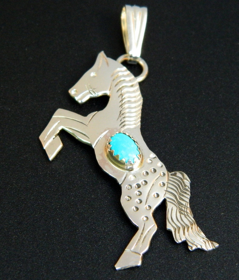 May include: Sterling silver pendant featuring a rearing horse design with a turquoise stone inlay. The horse is detailed with textured lines and dots.