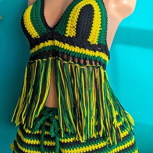 Pu&ograve; includere: Un set di bikini in crochet composto da top e gonna a righe verdi, nere e gialle. Il top ha frange e la gonna ha una chiusura a laccio.