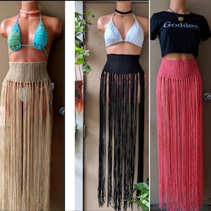 May include: Three crochet skirts with fringe. The skirts are beige, black, and coral. The skirts are shown on mannequins wearing different tops.