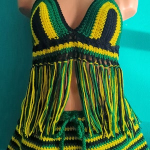 Pu&ograve; includere: Un set di top e gonna in crochet nero, verde e giallo. Il top ha uno stile halter e un bordo a frangia. La gonna ha un motivo a righe e una vita con coulisse.