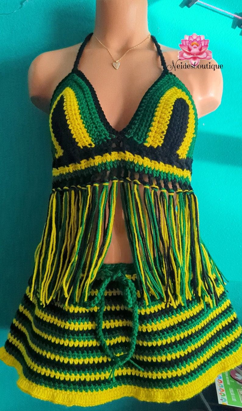 Pu&ograve; includere: Un set di top e gonna in crochet nero, verde e giallo. Il top ha uno stile halter e un bordo a frangia. La gonna ha un motivo a righe e una vita con coulisse.