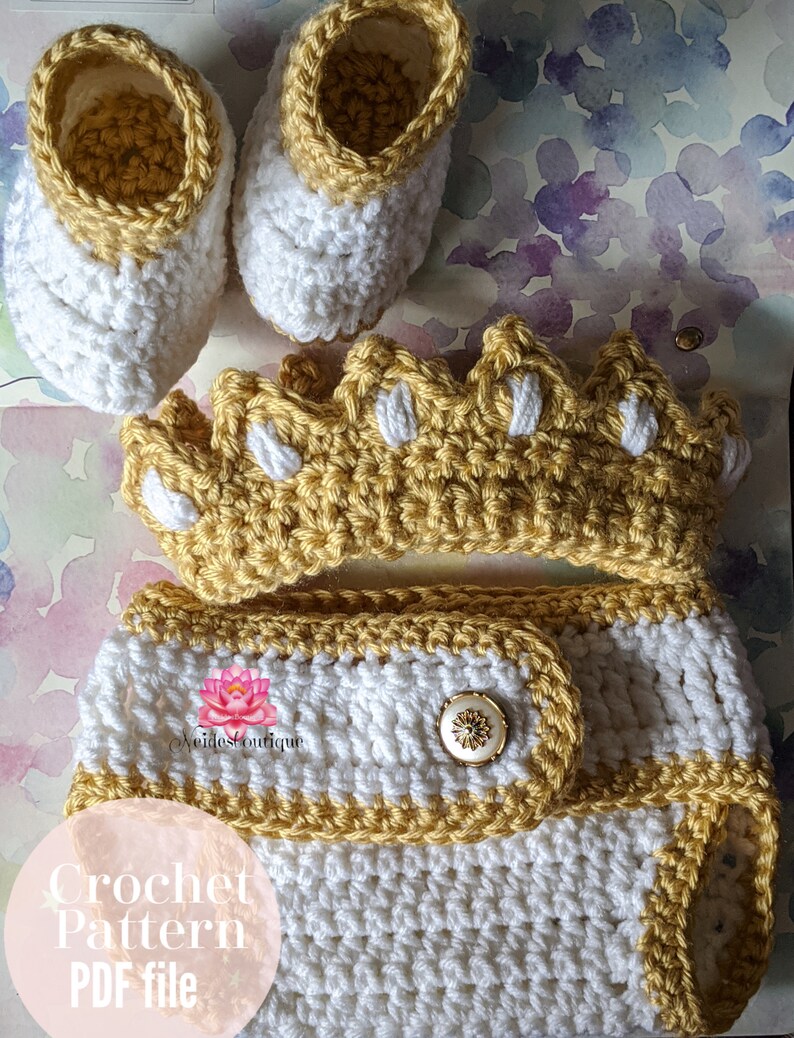 May include: Crochet pattern PDF file for a baby outfit. The outfit includes a crown, diaper cover, and booties. The crown and diaper cover are yellow and white, and the booties are white with yellow trim.