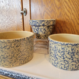 May include: Three ceramic bowls with a blue and white speckled glaze. The bowls are different sizes and shapes.