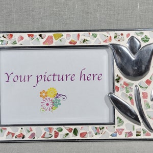 May include: Rectangular photo frame with a mosaic border of colorful ceramic pieces. A silver tulip design adorns the right side. The frame holds a white card with the text "Your picture here" and a floral graphic.