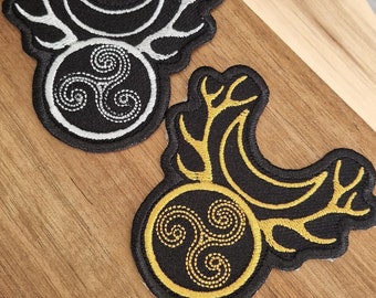 May include: Two embroidered patches with a black background and a gold or silver Celtic knot design. The knot is surrounded by a circle with antlers on either side.