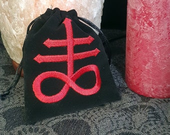 May include: A black velvet pouch with a red embroidered symbol, resembling a stylized cross with an infinity symbol at the bottom.