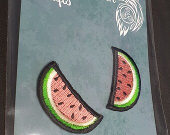 May include: Two watermelon slice patches. Each patch features a pink interior with black seeds, a green rind, and a black border. The patches are on a teal background with the text "Whyte Raven Crafts".