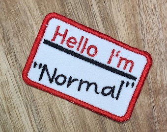 May include: Red and white embroidered patch with the text "Hello I'm "Normal""