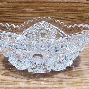 May include: A clear glass bowl with a cut glass design. The bowl is oval shaped and has a scalloped edge.