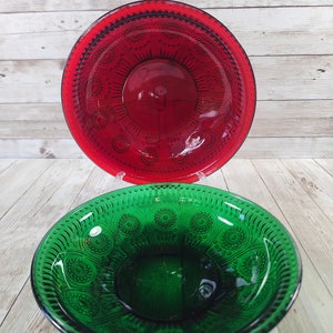 May include: Two glass bowls, one red and one green, with a decorative pattern. The bowls are made of glass and have a vintage look.