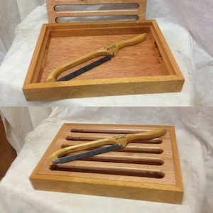 May include: A wooden bread board with a built-in bread knife. The board has five slots for scoring bread and the knife has a wooden handle.