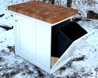 Puede incluir: Isla de cocina blanca con encimera de carnicero y un contenedor de basura extraíble. La isla tiene dos puertas de armario y está sobre ruedas.