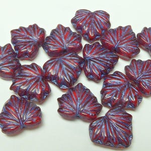 May include: A collection of leaf-shaped beads in shades of red and blue. The beads have a detailed, veined design and are made of a translucent material. These decorative beads are ideal for jewellery making and craft projects.